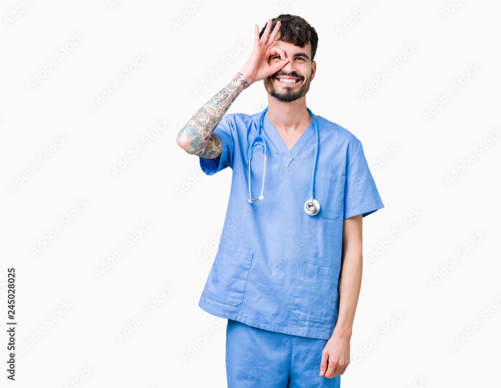 Young handsome nurse man wearing surgeon uniform over isolated background doing ok gesture with hand smiling, eye looking through fingers with happy face. Young handsome nurse man wearing surgeon uniform over isolated background doing ok gesture with hand smiling, eye looking through fingers with happy face.