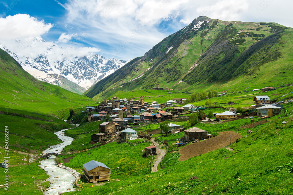 Georgian Svan village in the mountains in bright spring colors, blue sky and green mountains
