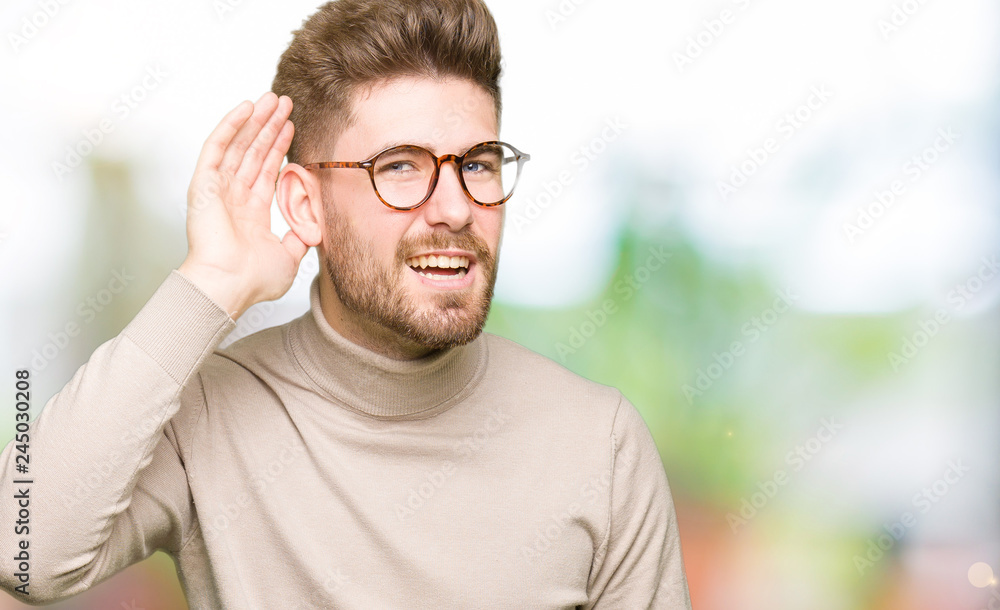 Young handsome business man wearing glasses smiling with hand over ear listening an hearing to rumor or gossip. Deafness concept. Young handsome business man wearing glasses smiling with hand over ear listening an hearing to rumor or gossip. Deafness concept.