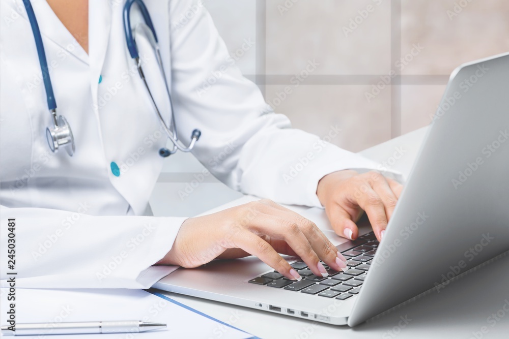 Close-up Doctor at hospital working with laptop Close-up Doctor at hospital working with laptop