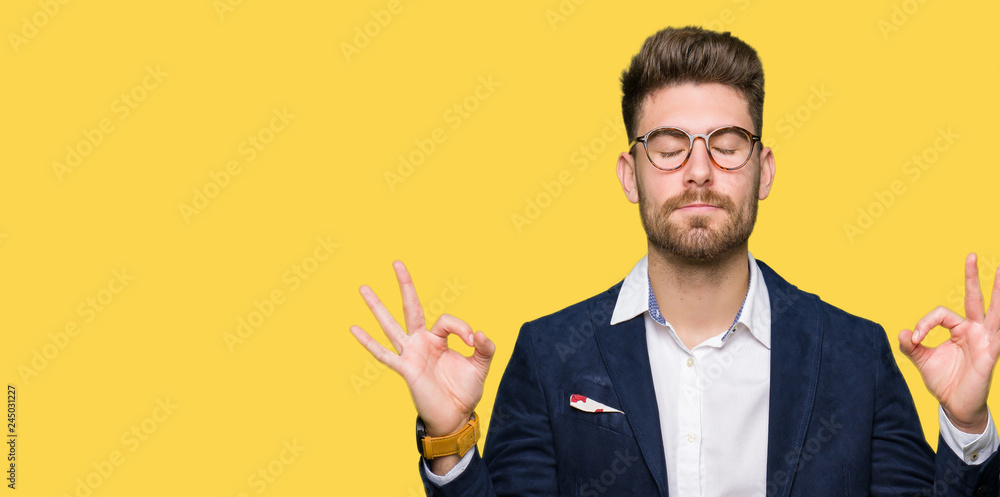 Young handsome business man wearing glasses relax and smiling with eyes closed doing meditation gesture with fingers. Yoga concept. - obrazy, fototapety, plakaty 