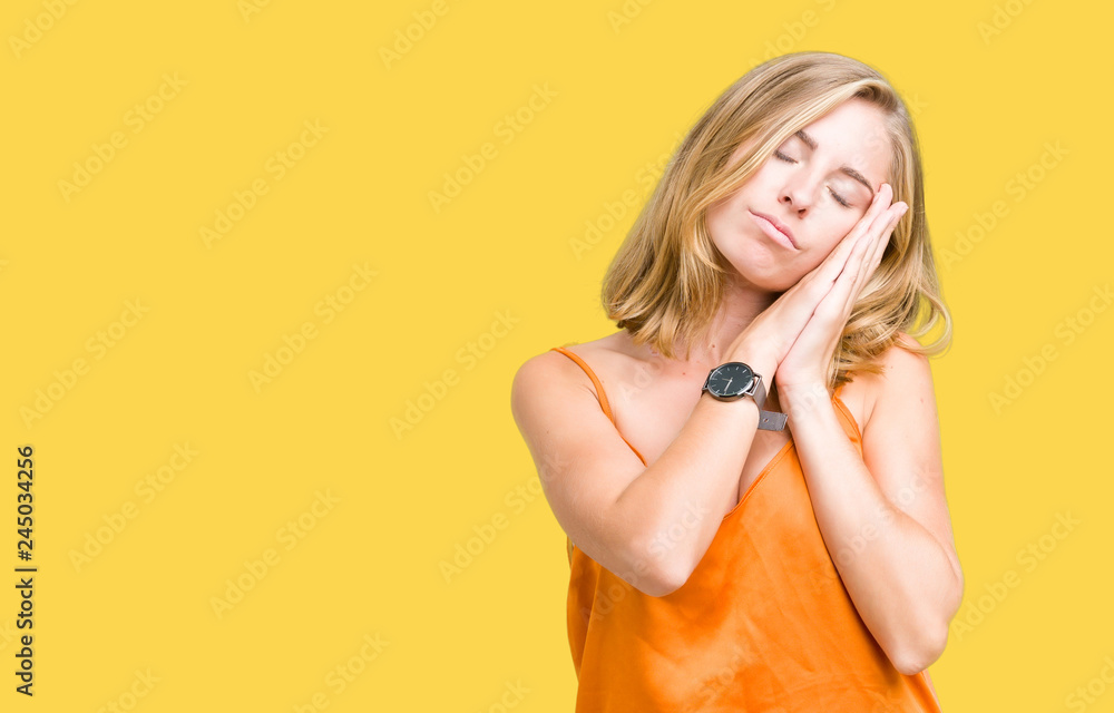 Beautiful young woman wearing orange shirt over isolated background sleeping tired dreaming and posing with hands together while smiling with closed eyes. Beautiful young woman wearing orange shirt over isolated background sleeping tired dreaming and posing with hands together while smiling with closed eyes.
