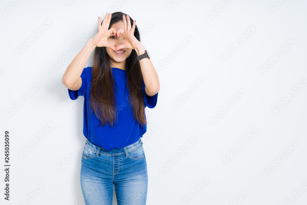 Beautiful brunette woman over isolated background Doing heart shape with hand and fingers smiling looking through sign Beautiful brunette woman over isolated background Doing heart shape with hand and fingers smiling looking through sign