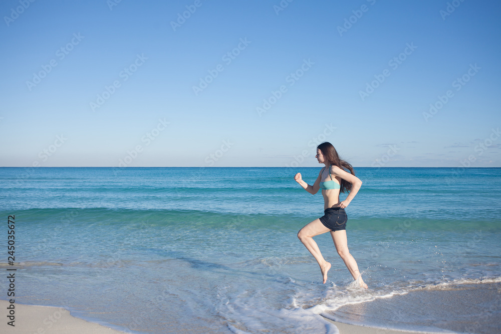 Young woman in shorts running on the beach Young woman in shorts running on the beach