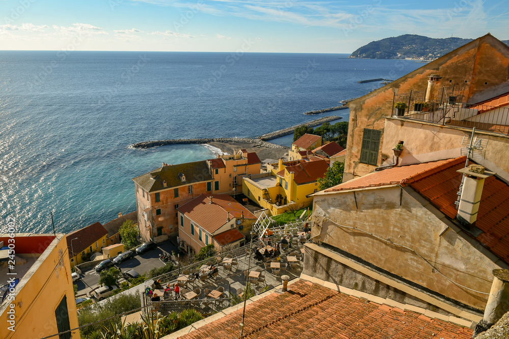 Panoramic view from above of the medieval borough of Cervo Ligure with tourists in an outdoor café, Liguria, Italy