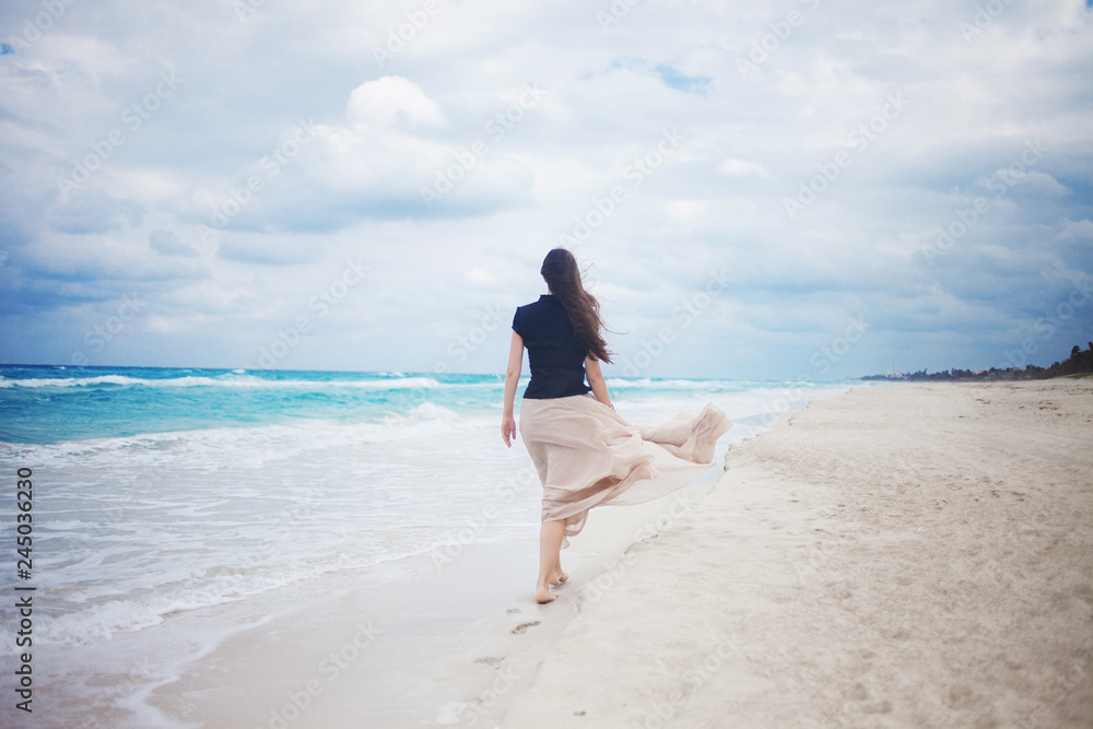 young woman in a long skirt walking on the ocean. 