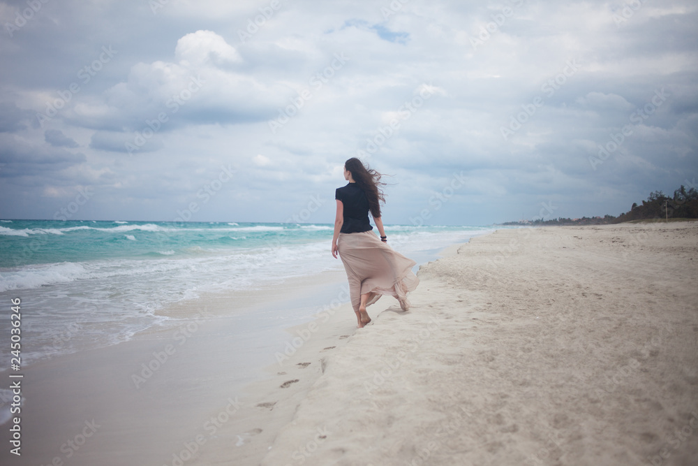 young woman in a long skirt walking on the ocean. young woman in a long skirt walking on the ocean.