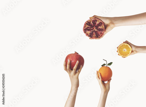 Hands holding orange and pomegranate on isolated background