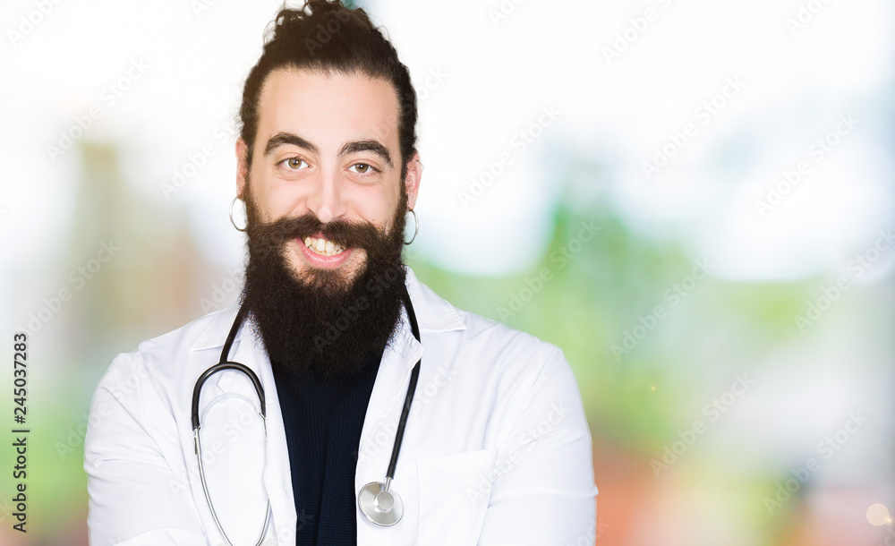 Doctor with long hair wearing medical coat and stethoscope Smiling with hands palms together receiving or giving gesture. Hold and protection