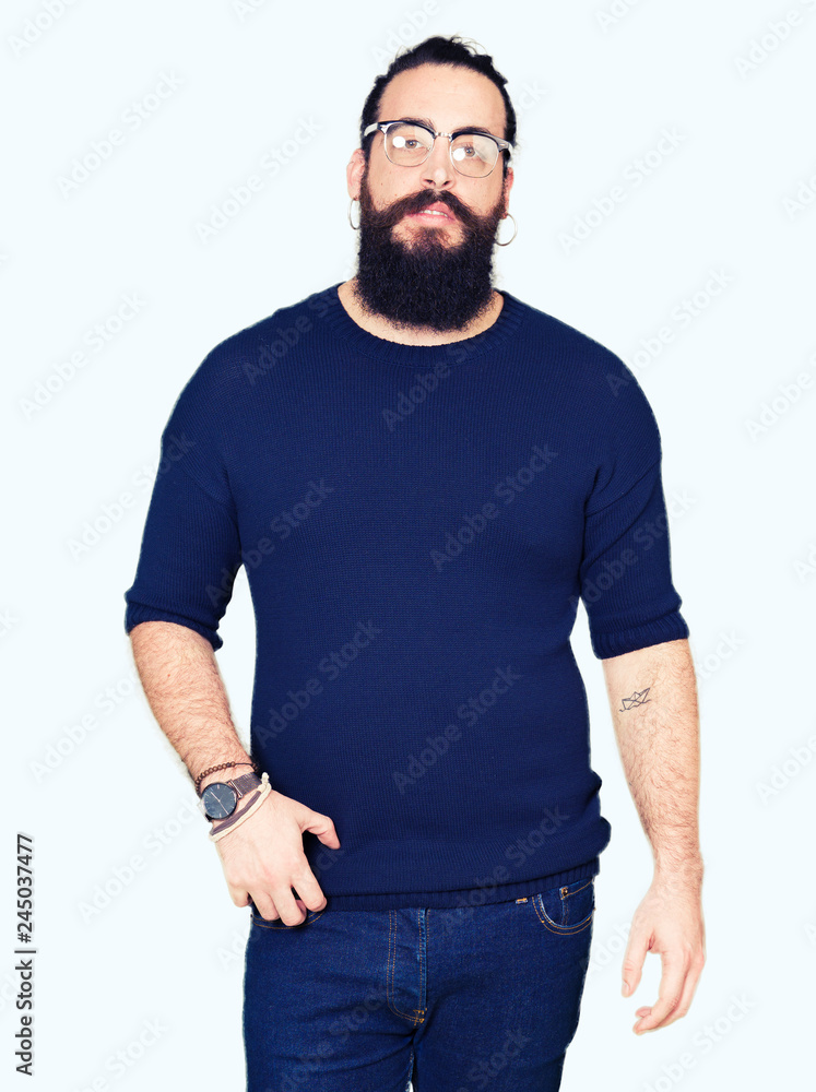 Young hipster man with long hair and beard wearing glasses Relaxed with serious expression on face. Simple and natural looking at the camera. Young hipster man with long hair and beard wearing glasses Relaxed with serious expression on face. Simple and natural looking at the camera.