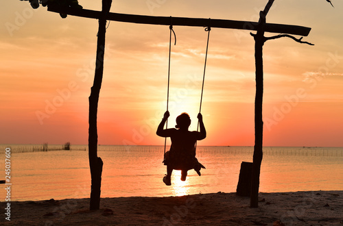Girl on a swing enjoying the orange sunset at Belitung Island, Indonesia