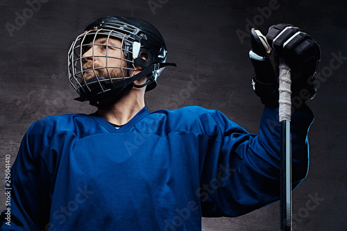 Photography Portrait of a bearded ice-hockey player in a blue sportswear with gaming stick
