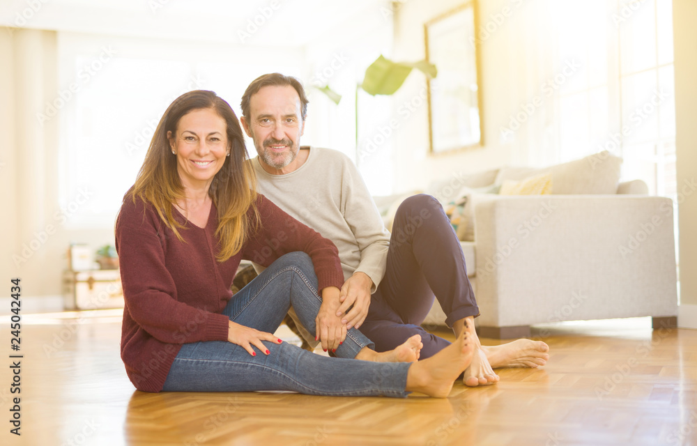 Beautiful romantic couple sitting together on the floor with the cat at home Beautiful romantic couple sitting together on the floor with the cat at home