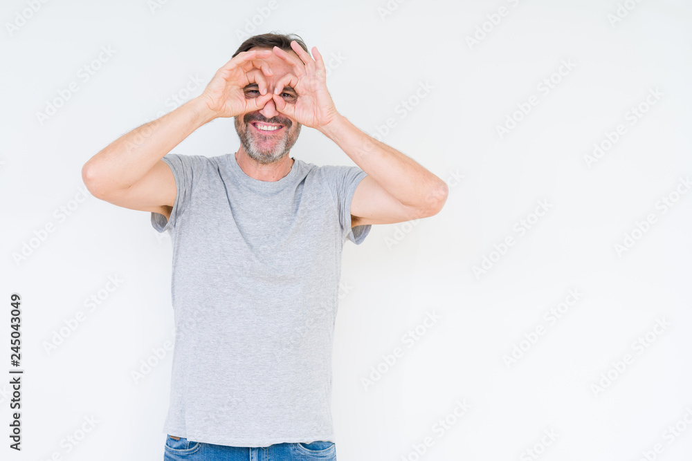 Handsome senior man over isolated background doing ok gesture like binoculars sticking tongue out, eyes looking through fingers. Crazy expression. Handsome senior man over isolated background doing ok gesture like binoculars sticking tongue out, eyes looking through fingers. Crazy expression.