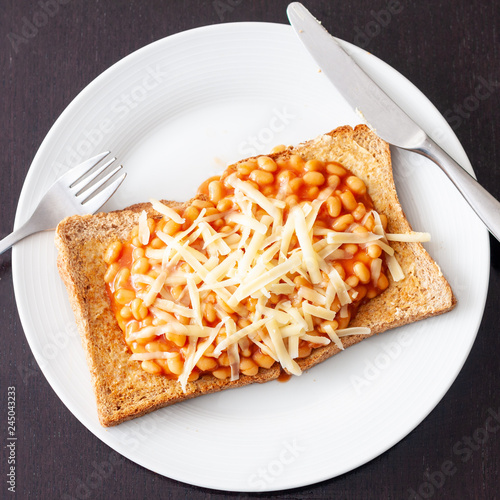 Overhead view of baked beans on toast topped with grated cheese