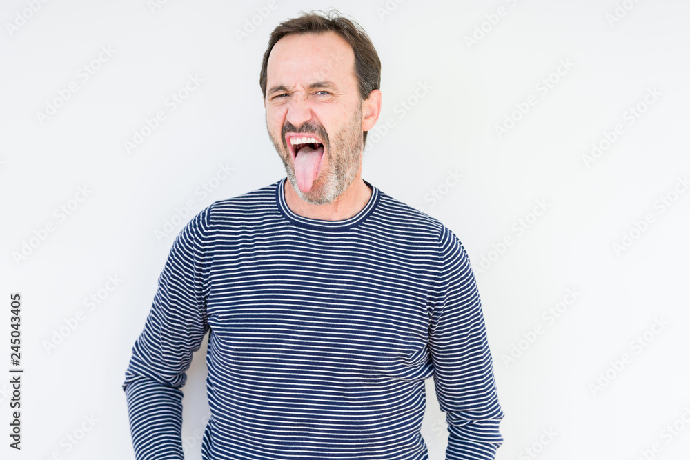 Obraz premium Handsome senior man over isolated background sticking tongue out happy with funny expression. Emotion concept.