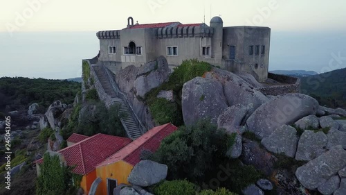 Aerial, reverse, drone shot away from the Santuario da Peninha chapel, up in the mountains, on a sunny evening dusk, in Sintra, Portugal photo