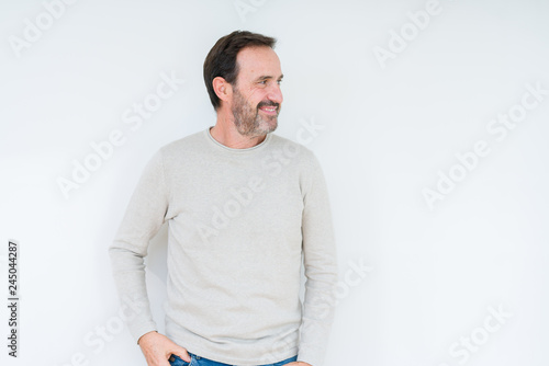 Elegant senior man over isolated background looking away to side with smile on face, natural expression. Laughing confident.