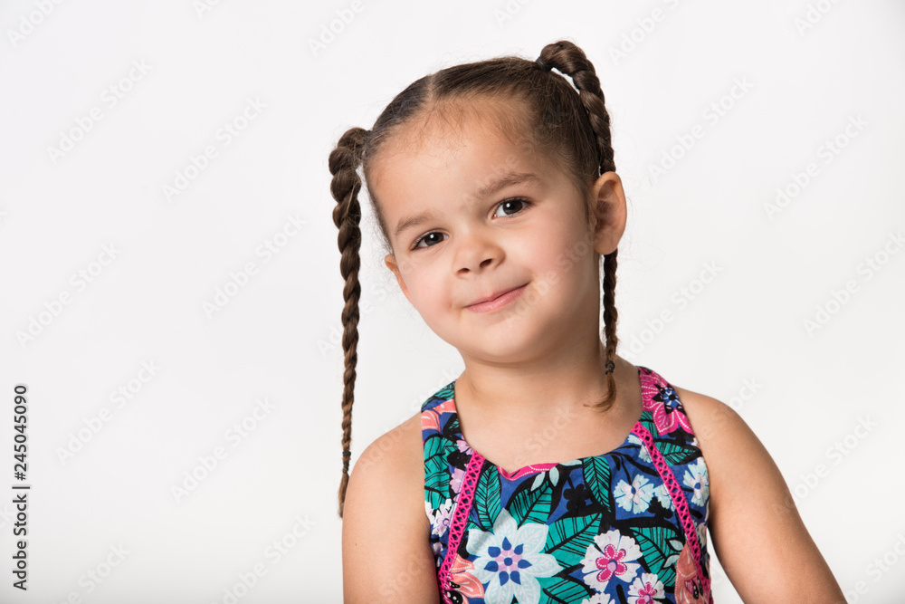 Mixed race preschooler with brown pigtail braids and playful expression Mixed race preschooler with brown pigtail braids and playful expression