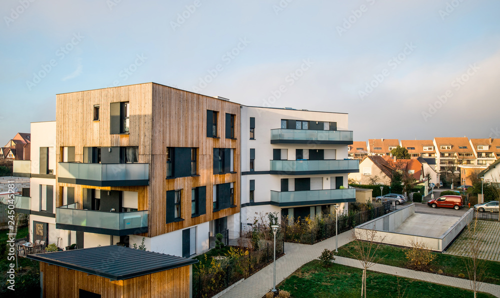 Modern townhouses in a residential area with multiple new apartments buildings surrounded by green outdoor facilities with cars parked on the street