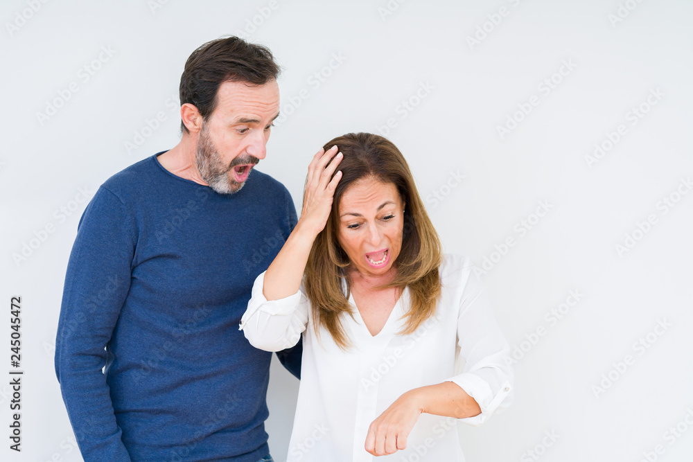 Beautiful middle age couple in love over isolated background Looking at the watch time worried, afraid of getting late Beautiful middle age couple in love over isolated background Looking at the watch time worried, afraid of getting late