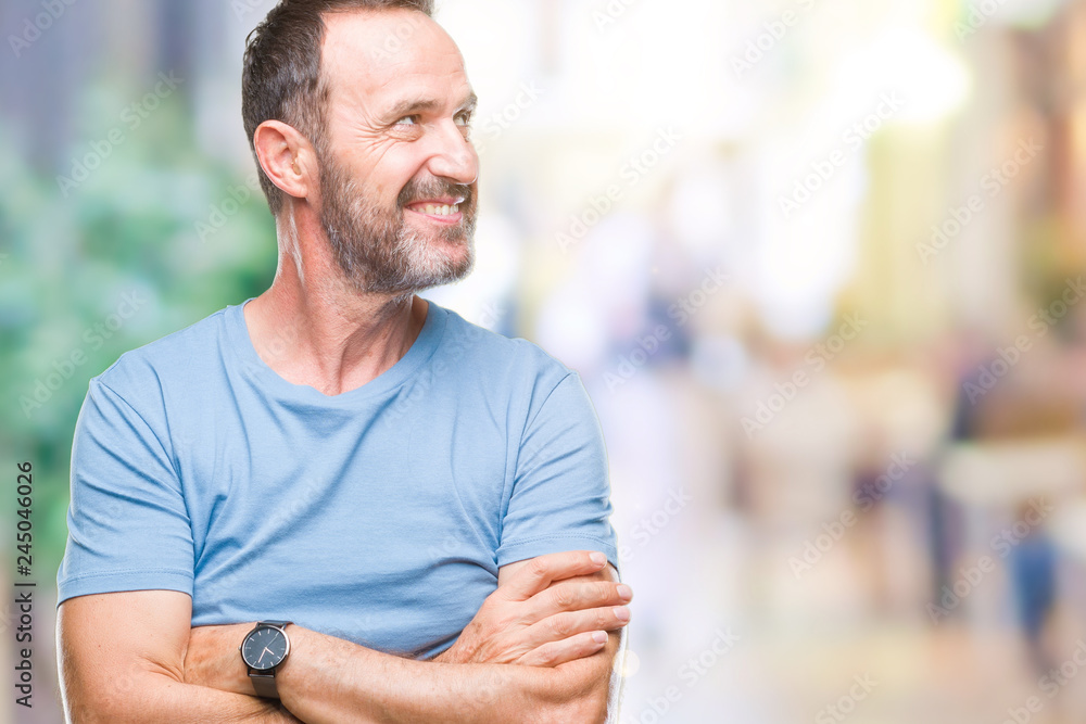 Fototapeta premium Middle age hoary senior man over isolated background looking away to side with smile on face, natural expression. Laughing confident.
