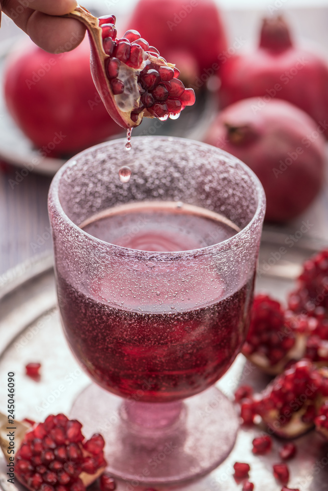 A glass of pomegranate juice with fresh pomegranate fruits and seeds on rustic background. A glass of pomegranate juice with fresh pomegranate fruits and seeds on rustic background.