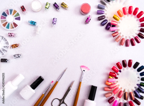 A set of cosmetic tools for manicure and pedicure on a weyt background. Gel polishes, nail files and clippers, and the lamp top view. Composition for card with a place for text