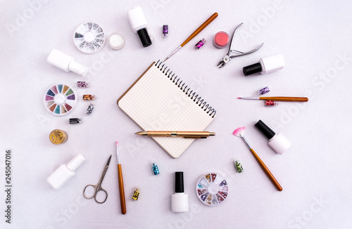 A set of cosmetic tools for manicure and pedicure on a weyt background. Gel polishes, nail files and clippers, and the lamp top view. Composition for card with a place for text