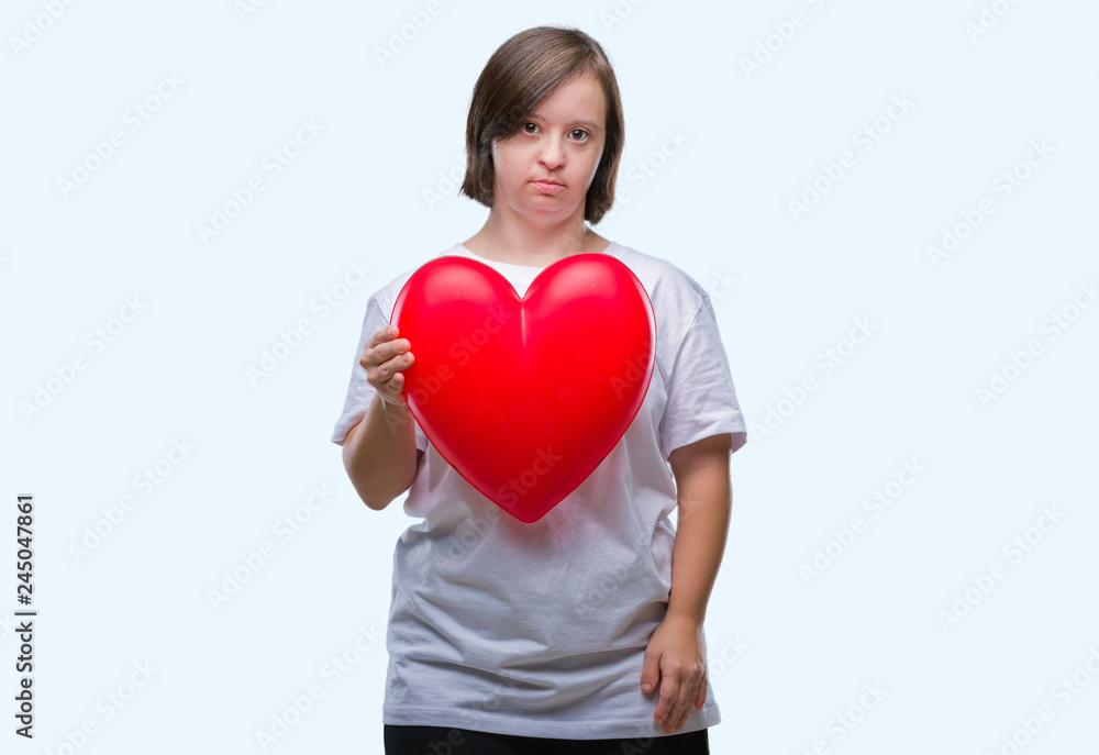 Young adult woman with down syndrome holding red heart over isolated background with a confident expression on smart face thinking serious Young adult woman with down syndrome holding red heart over isolated background with a confident expression on smart face thinking serious