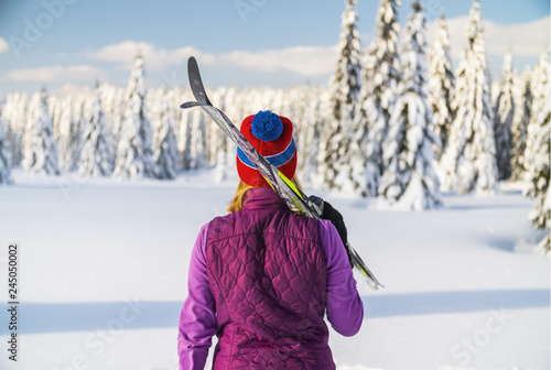 Canvas Print Back view of female skier in a snowy trees.