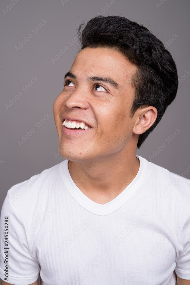 Portrait of young Asian man against gray background Portrait of young Asian man against gray background