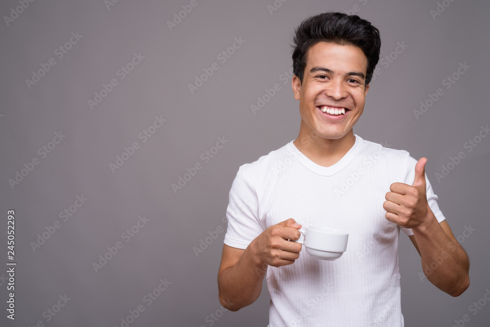Portrait of young Asian man against gray background Portrait of young Asian man against gray background