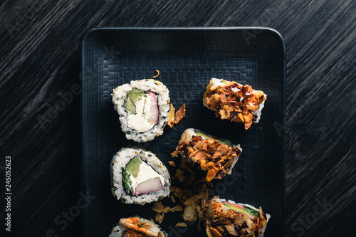 Sushi rolls on dark wood table.