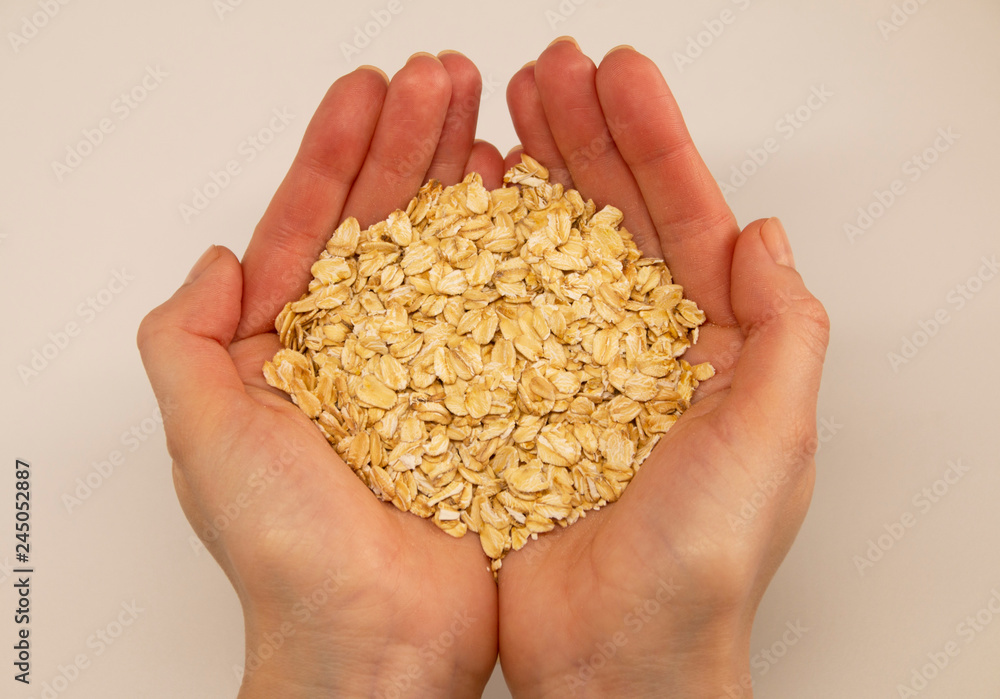 oat grain in the palms on a white background, top view oat grain in the palms on a white background, top view