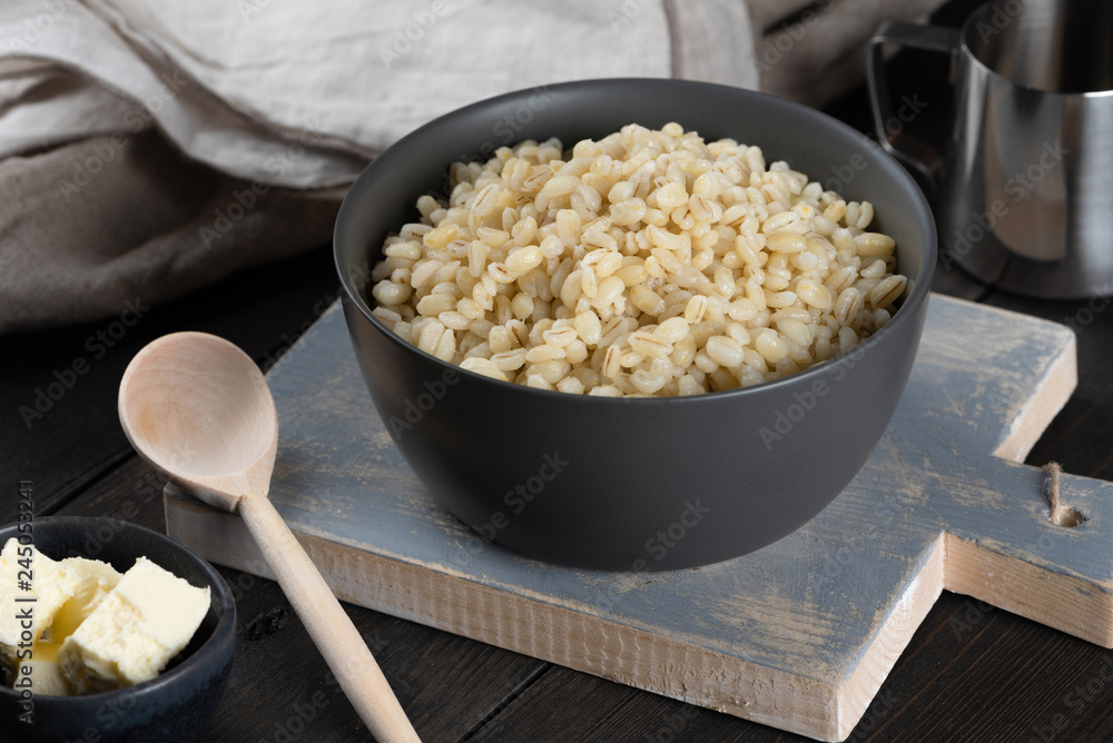 Pearl barley porridge in a plate on a black wooden background
