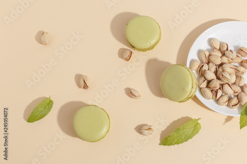 Pistachio cake makaroons and forex pistachios on a beige background. Top view. photo