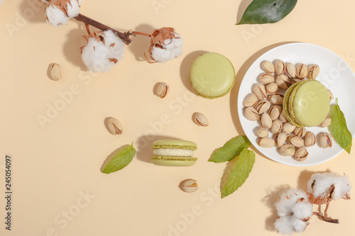 Pistachio cake makaroons and forex pistachios on a beige background. Top view. photo