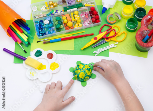 The child makes a craft toy from foam plastic tortoise. Material for creativity and education.