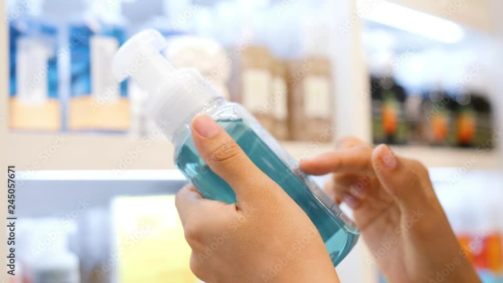 Young Woman Choosing Shower Gel and Reading Product Composition on a Bottle in Cosmetics Store. 4K Slowmotion. Consumerism Concept Footage in Beauty shop. Bali, Indonesia. Young Woman Choosing Shower Gel and Reading Product Composition on a Bottle in Cosmetics Store. 4K Slowmotion. Consumerism Concept Footage in Beauty shop. Bali, Indonesia.