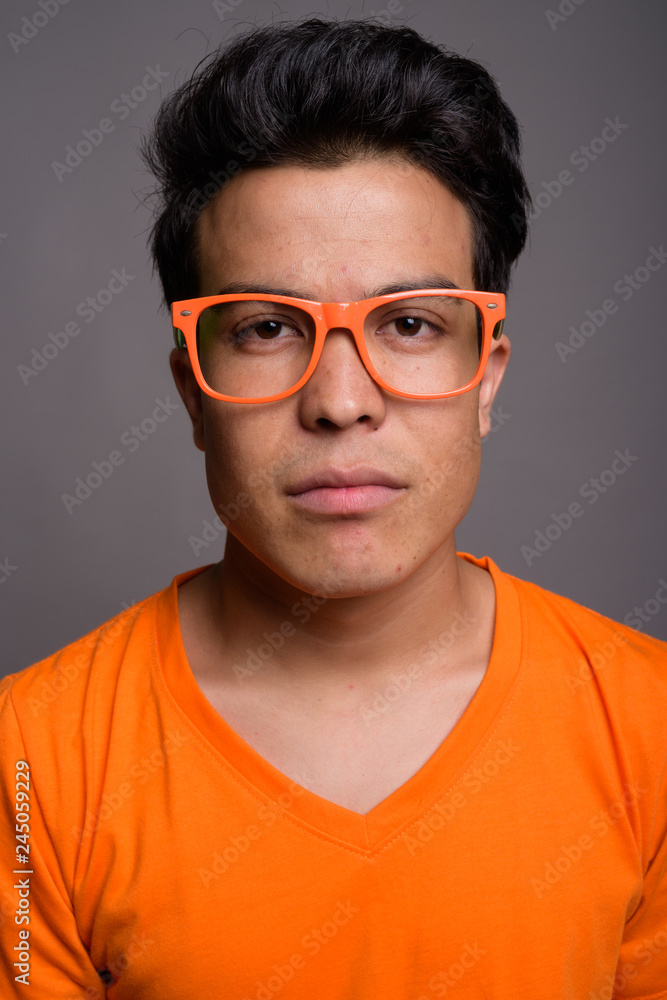 Portrait of young Asian man against gray background Portrait of young Asian man against gray background