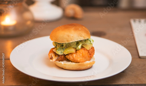 Fish sandwich  fried cod burger with sweet pickle  tartar sauce  fresh bun  candlelight