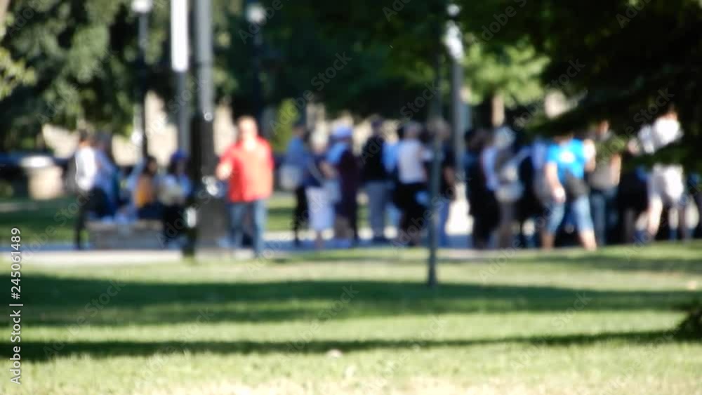 Blurred People Standing In Line With Man In Orange Shirt Walking Towards Camera Blurred People Standing In Line With Man In Orange Shirt Walking Towards Camera