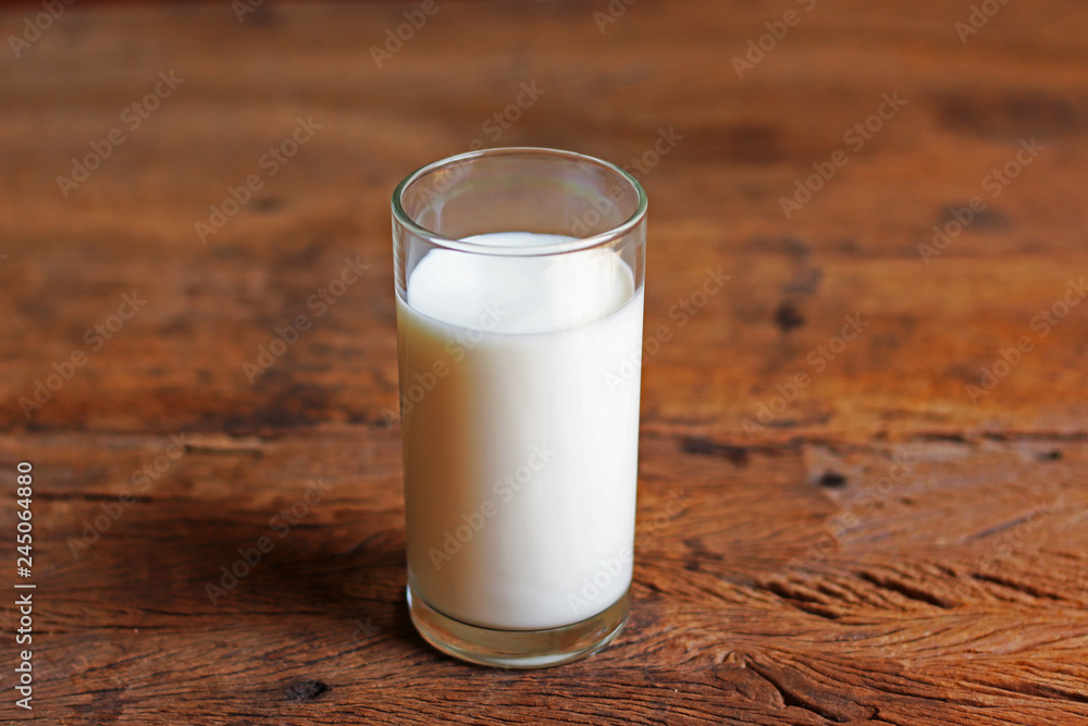 A glass of fresh milk on wooden table A glass of fresh milk on wooden table