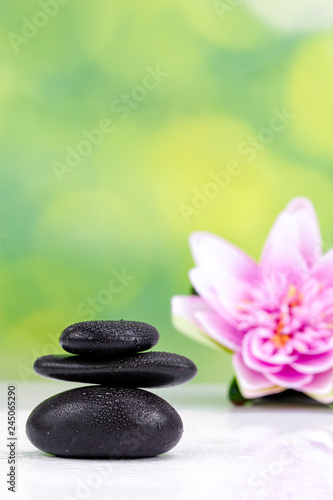 Balanced zen stones with drops of water on a green bokeh background