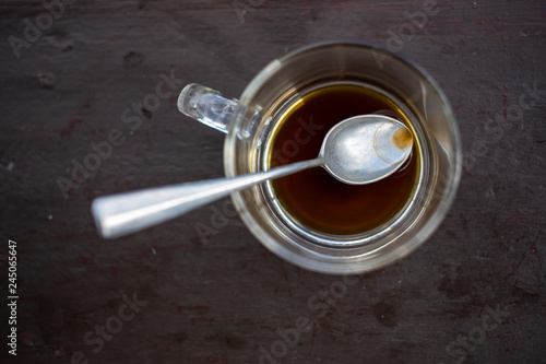 Glass coffee cup, finished americano coffee drink left over and siver spoon on wooden table background, Close up shot, Selective focus