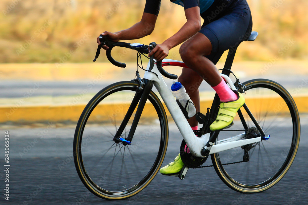 Fototapeta premium close up of a road cyclist riding a white carbon frame holding the bike handlebar during a road race competition,