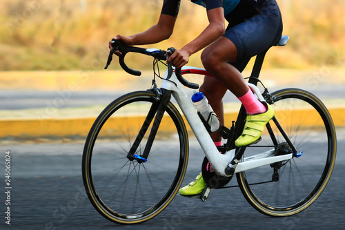 close up of a road cyclist riding a white carbon frame holding the bike handlebar during a road race competition 