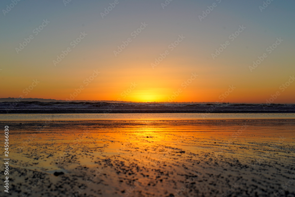 Bright orange serene beach sunset at low tide with no people