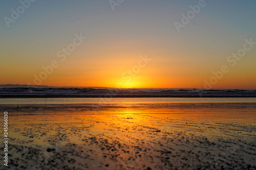 Bright orange serene beach sunset at low tide with no people